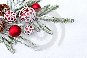 Christmas decoration. Red balls with white openwork, cones, branch christmas tree on snow with space for text