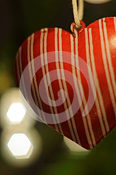 Christmas decoration. Red heart hanging on xmas tree. Lights. Background bokeh.