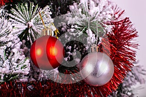 Christmas decoration red and silver balls in a tree with tinsel and pinecone in snow