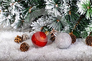 Christmas decoration red and silver balls in a tree with tinsel and pinecone in snow