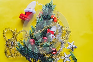 Christmas decoration. Santa`s boot,red ball, fir tree branches with cones and christmas toys on yellow background. Top view