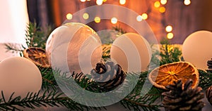 Christmas decoration set made of white Christmas balls, spruce sprigs, cones and dried oranges and lemons. Lightened lights in the