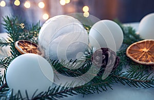 Christmas decoration set made of white Christmas balls, spruce sprigs, cones and dried oranges and lemons. Lightened lights in the