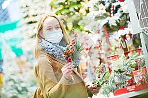 christmas decoration shopping. woman in mask buying new year decor in shop