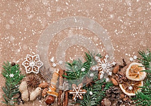 Christmas decoration with spices and cookies in the shape of snowflakes on dark brown paper background. Top view.