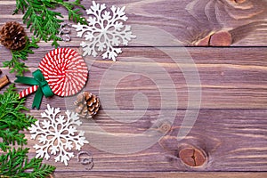Christmas decoration with thuja branches, snowflakes, pine cones and candy on wooden background