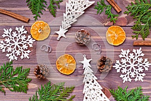 Christmas decoration with thuja branches, snowflakes, pine cones, cinnamon and mandarin on wooden background