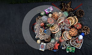 Christmas decoration. Twigs christmas tree, brown natural pine cones and and Xmas deer with variety of fruits on dark background.
