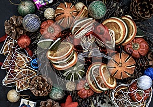 Christmas decoration. Twigs christmas tree, brown natural pine cones and and Xmas deer with variety of fruits on dark background.