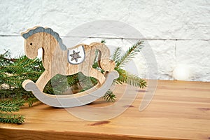 Christmas decoration with twigs of spruce and horse on the shelf on the background of a brick wall