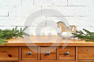 Christmas decoration with twigs of spruce and horse on the shelf on the background of a brick wall