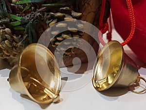 Christmas decoration, two golden bells and a red gift bag on a bright background.