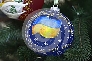 Christmas decoration, with Ukrainian national flag painted, hanging on a Christmas tree before New Year Day