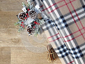 Christmas decoration on a warm winter blanket background top view. Mistletoe, pine-cone, pine tree branch, a bunch of cinnamon.