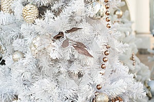 Christmas decoration, white Christmas tree with gold ornaments, leaf, garland and shiny balls. Christmas background