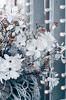 Christmas decoration with white flowers, bronze leaves and lights