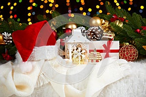 Christmas decoration on white fur with fir tree branch closeup, gifts, xmas ball, cone and other object on dark background with li