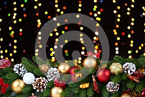 Christmas decoration on white fur with fir tree branch closeup, gifts, xmas ball, cone and other object on dark background, lights