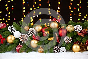 Christmas decoration on white fur with fir tree branch closeup, gifts, xmas ball, cone and other object on dark background, lights
