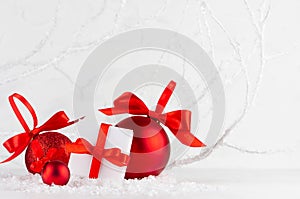 Christmas decoration - white gift boxes and glossy red balls with satin ribbon in decorative soft light winter forest with frosty.