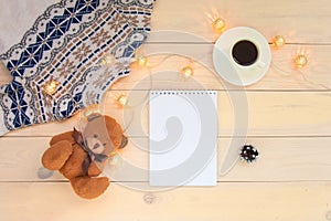 Christmas decoration wooden background with knitted wool sweater with jacquard ornament, brown bear toy, cup of coffee., christmas