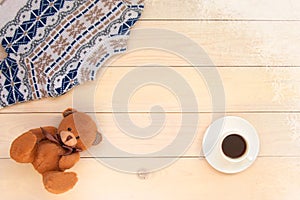 Christmas decoration wooden background with knitted wool sweater with jacquard ornament in white blue and beige. brown bear toy,