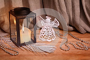 Christmas decoration on wooden background. White crochet angel, candle and lantern