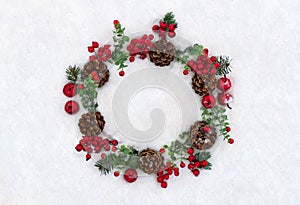 Christmas decoration. Wreath of twigs christmas tree, brown natural pine cones and red berries on snow with space for text