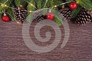 Christmas decorations with branches of fir tree, christmas lights, ball and Pine cones on wooden background. copy space