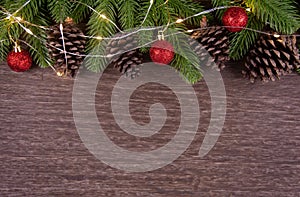 Christmas decorations with branches of fir tree, christmas lights, ball and Pine cones on wooden background. copy space