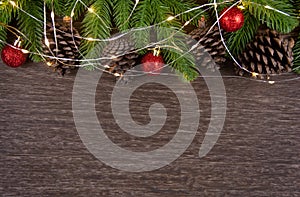 Christmas decorations with branches of fir tree, christmas lights, ball and Pine cones on wooden background. copy space