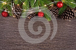 Christmas decorations with branches of fir tree, christmas lights, ball and Pine cones on wooden background. copy space