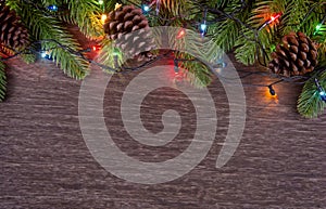 Christmas decorations with branches of fir tree, christmas lights, ball and Pine cones on wooden background. copy space