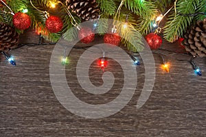 Christmas decorations with branches of fir tree, christmas lights, ball and Pine cones on wooden background. copy space