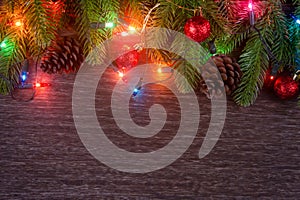 Christmas decorations with branches of fir tree, christmas lights, ball and Pine cones on wooden background. copy space