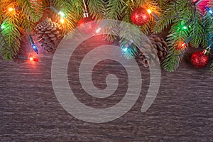 Christmas decorations with branches of fir tree, christmas lights, ball and Pine cones on wooden background. copy space