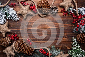 Christmas decorations on a brown wood background with copy space. Pine cones, garland, berries and pine branches