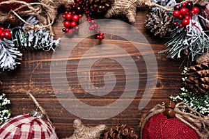 Christmas decorations on a brown wood background with copy space. Pine cones, garland, berries and pine branches