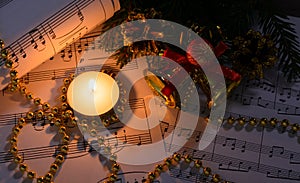 Christmas decorations, burning candle and sheet music