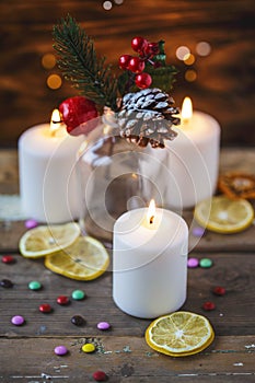 Christmas decorations, burning candles, candy ,citrus, spruce on a wooden background. New Year`s concept. Postcard