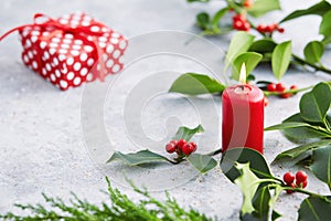 Christmas decorations, candle and holly leaves with red berries.