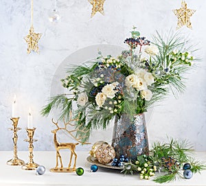 Christmas decorations, candles and flower bouquet. Winter arrangement with roses, fir branches, winter berries. Christmas flower