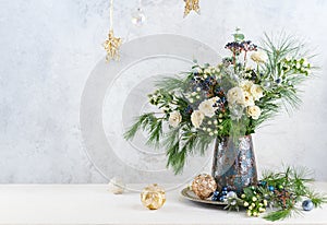 Christmas decorations, candles and flower bouquet. Winter arrangement with roses, fir branches, winter berries. Christmas flower