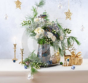 Christmas decorations, candles, gift boxes and flower bouquet. Winter arrangement with roses, fir branches, winter berries.