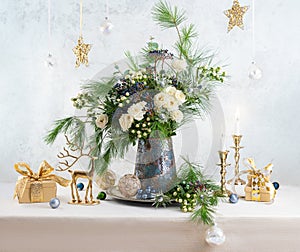 Christmas decorations, candles, gift boxes and flower bouquet. Winter arrangement with roses, fir branches, winter berries.