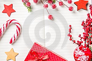 Christmas decorations, candy cane, frozen red berries, stars and gift box frame on notebook, copy space for text. Can be used for