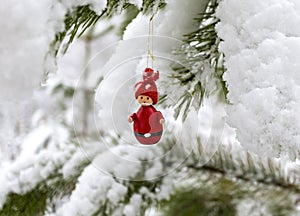 Christmas decorations Christmas tree toy red gnome hanging on a snow-covered pine branch in the winter forest