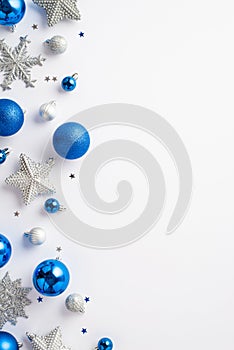 Christmas decorations concept. Top view vertical photo of blue white silver baubles snowflake star ornaments and confetti on
