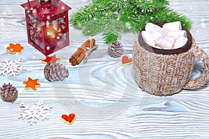 Christmas Decorations with cup of hot cocoa, lamp with candle, cinnamon sticks, pine, fir branch on wooden light blue table.