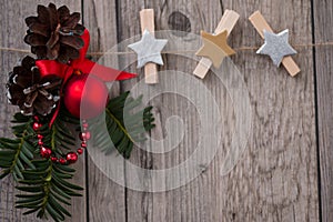 Christmas decorations with evergreen tree twigs, pine cone, red ball and wooden peg clips in form star.